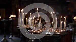 Candles burn in an Orthodox church. Wax candles burn in the dark in church against dark background close-up camera movement.