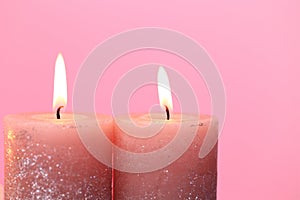 Candles. Burning candles on a pink background. Festive shiny candles. Flame candles close-up.