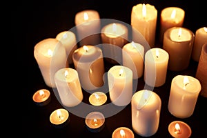 Candles burning in darkness over black background