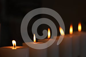a diagonal row of 6 flickering solemn candles with yellow flames photo