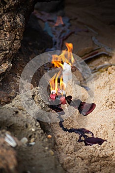 Candles burning among rocks on a beach to honor some religious entity