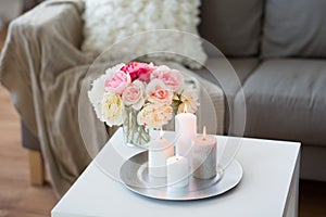 Candles burning on table and flowers at cozy home