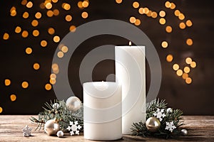 Candles and Christmas decor on table against blurred festive lights. Winter holiday