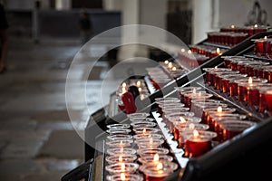 Candles in the Church. Votive prayer candles inside a catholic church on a candle rack