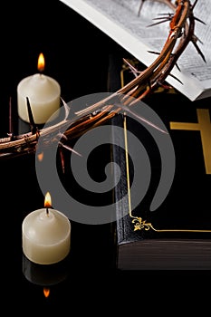 Candles with crown of thorns and Holy Scripture on black background