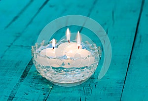 Candles floating in glass bowl on rustic table