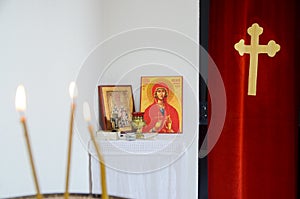 Candles in front of icons in the Orthodox church. A burning wax candles, cross and icons in monastery. Christian religion. Altar i