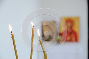 Candles in front of icons in the Orthodox church. A burning wax candles, cross and icons in monastery. Christian religion. Altar i