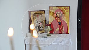 Candles in front of icons in the Orthodox church. A burning wax candles, cross and icons in monastery. Christian religion. Altar i