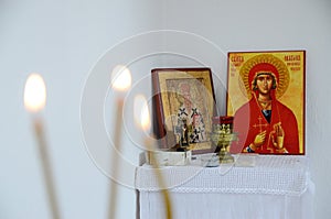 Candles in front of icons in the Orthodox church. A burning wax candles, cross and icons in monastery. Christian religion. Altar i