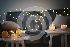 Candles and garlands on a gray sofa in the living room, christmas and new year comfort at home concept