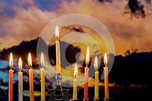 Candles on hanukkah menorah against cramatic sunset