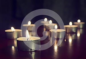 Candles lights on dark background. Light of candle flame, holiday background.