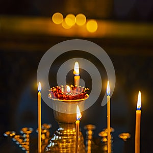 Candles are lit in gold vase, religion and sad concept