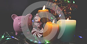 Candles lit up with Christmas trees pink piggy bank and party lights, Enjoy savings for the holidays concept