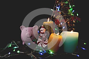 Candles lit up with Christmas trees pink piggy bank and party lights, Enjoy savings for the holidays concept