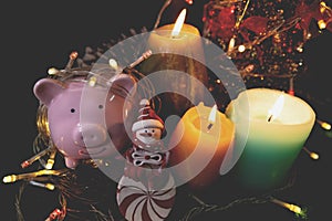 Candles lit up with Christmas trees pink piggy bank and party lights, Enjoy savings for the holidays concept