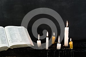 Candles on an old wooden burnt table. Beautiful dark background. Religious concept.