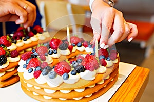 candles put on the cake with berries in the form of the number ten. photo