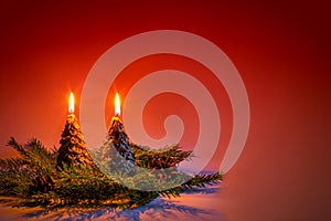 Candles in the shape of Christmas trees on a red background.