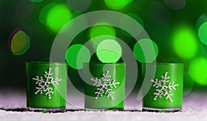Candles standing in snow with defocussed fairy lights, green bokeh in the background, Festive Christmas background photo
