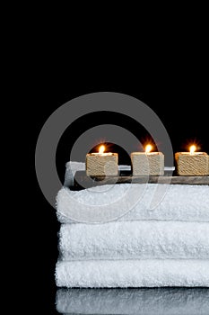 Candles on three spa towels on black