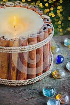 Candlestick of cinnamon sticks with christmas decoration and branch of fir background with bokeh