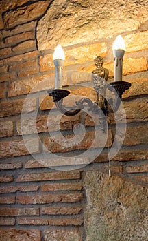 Candlestick with lamp on brick wall in ancient building. Medieval interior. Stone and brick old house.