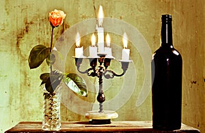 A candlestick a rose is an excellent bottle of red wine