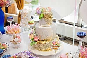 Candy bar on golden wedding party with a lot of different candies, cupcakes, souffle and cakes. Decorated in brown and purple colo