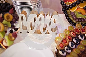 Love logo on candy bar.Different delicious fruits and cookies on wedding reception table with bananas and grapes photo