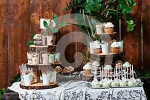 Candy bar on wooden wedding party with a lot of different candies, cupcakes, souffle and cakes