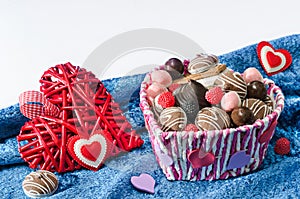 Candy basket, cookies and a decorative Valentines day hearts on blue velvet cloth white background.