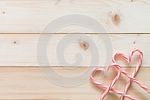 Candy cane in heart love shape on white pine wood knotty table background for Christmas food backdrop, Valentine`s day