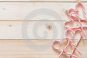 Candy cane in heart love shape on white pine wood knotty table background for Christmas food backdrop, Valentine`s day