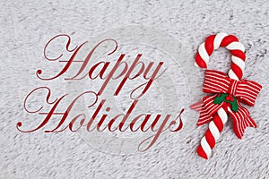 Candy cane on plush gray material with text Happy Holidays