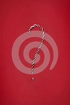 Candy cane question mark on red background. Christmas striped candie