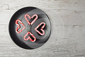 Candy canes arranged in heart shapes on black plate