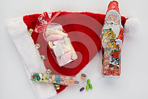 Candy canes, candies and chocolate on Santa hat isolated