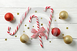 Candy canes and christmas accessories on white wooden background