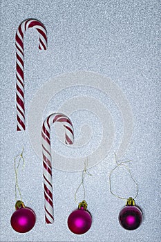 Candy canes and christmas balls on sparkling silver background, selective focus, copy space