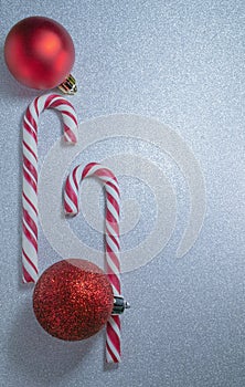 candy canes and christmas balls on sparkling silver background, selective focus, copy space