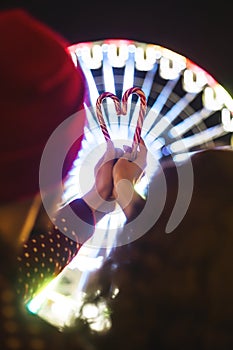 Candy canes in the shape of heart on the background of the ferris wheel