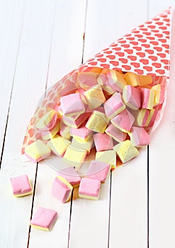 Candy cone spilling square marshmallows on a table