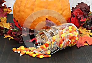 Candy corn in a mason jar spilling onto a table decorated for au