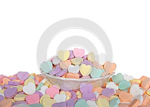 Candy hearts in porcelain bowl, surrounded by candy hearts. Isolated