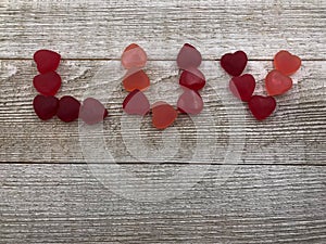 Candy hearts spell LUV on wood background