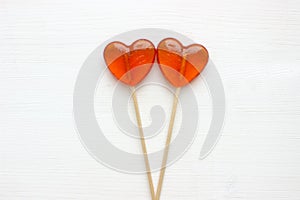 Candy hearts. Two heart shaped lollipops isolated on white wooden background