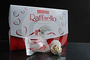 Candy and a square rectangular gift box by Raffaello stands on a black background side view of copy space