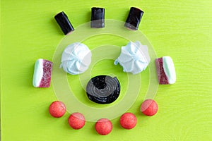 Candy teeth sweet smile flat lay colorful fruit marmalade, marshmallow and black licorice candies on green background